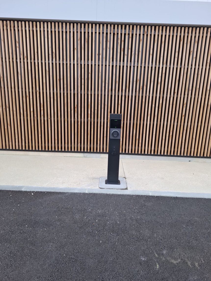 Borne de recharge sur pied installée devant un claustra bois · Cormeilles-en-Parisis