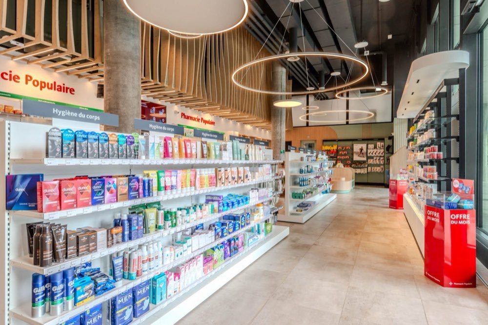 Intérieur de pharmacie éclairé par des suspensions circulaires LED et des rampes de rayonnage